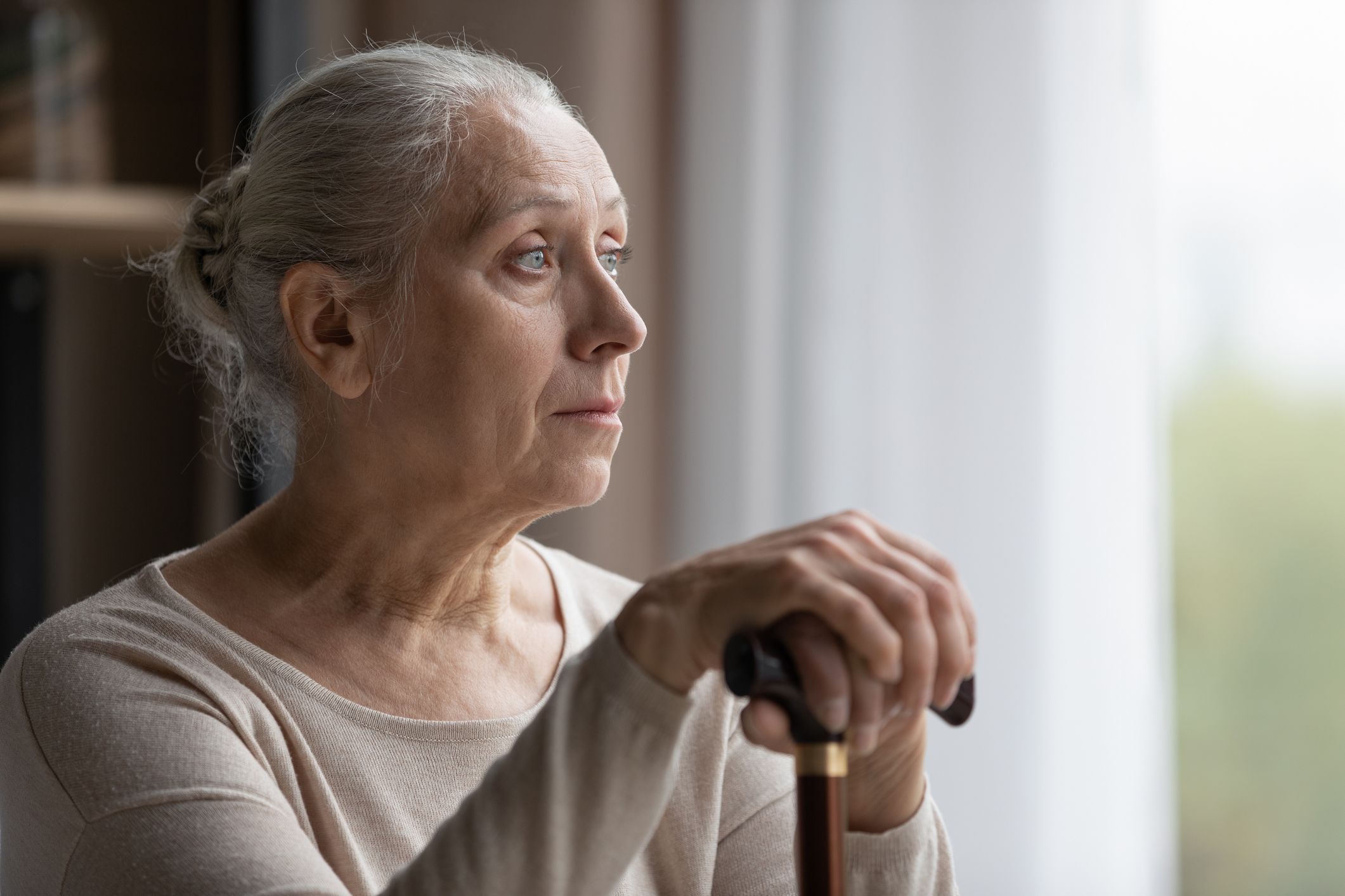 Elderly woman looks out window