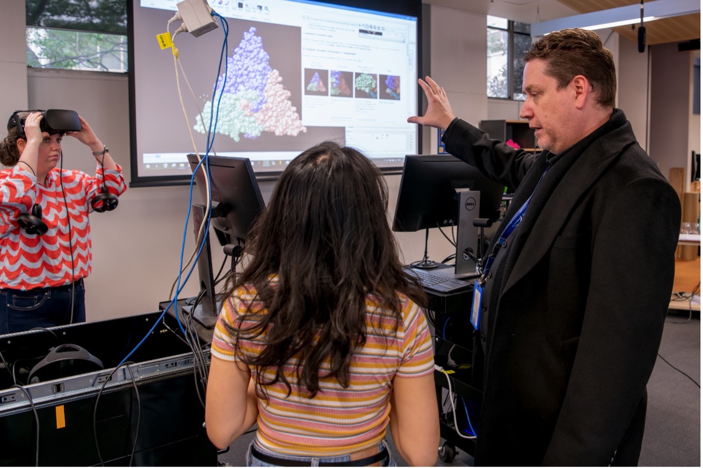 Dr. Jason Roberts (dreapta) îi învață pe studenți cum să manipuleze structurile virusului în realitate virtuală.