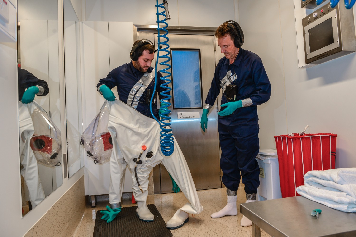 Dr Julian Druce heping Daniel suit up before entering the laboratory.